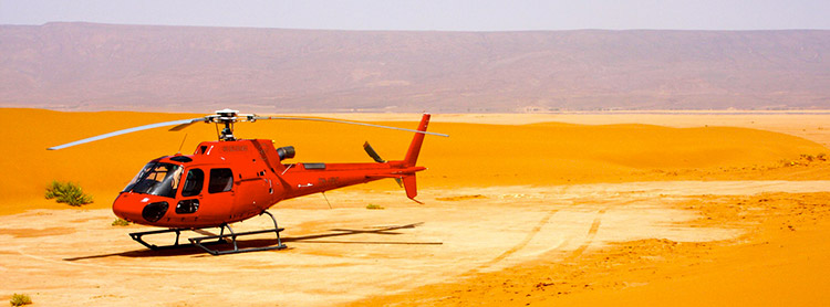 A helicopter landed on orange sand