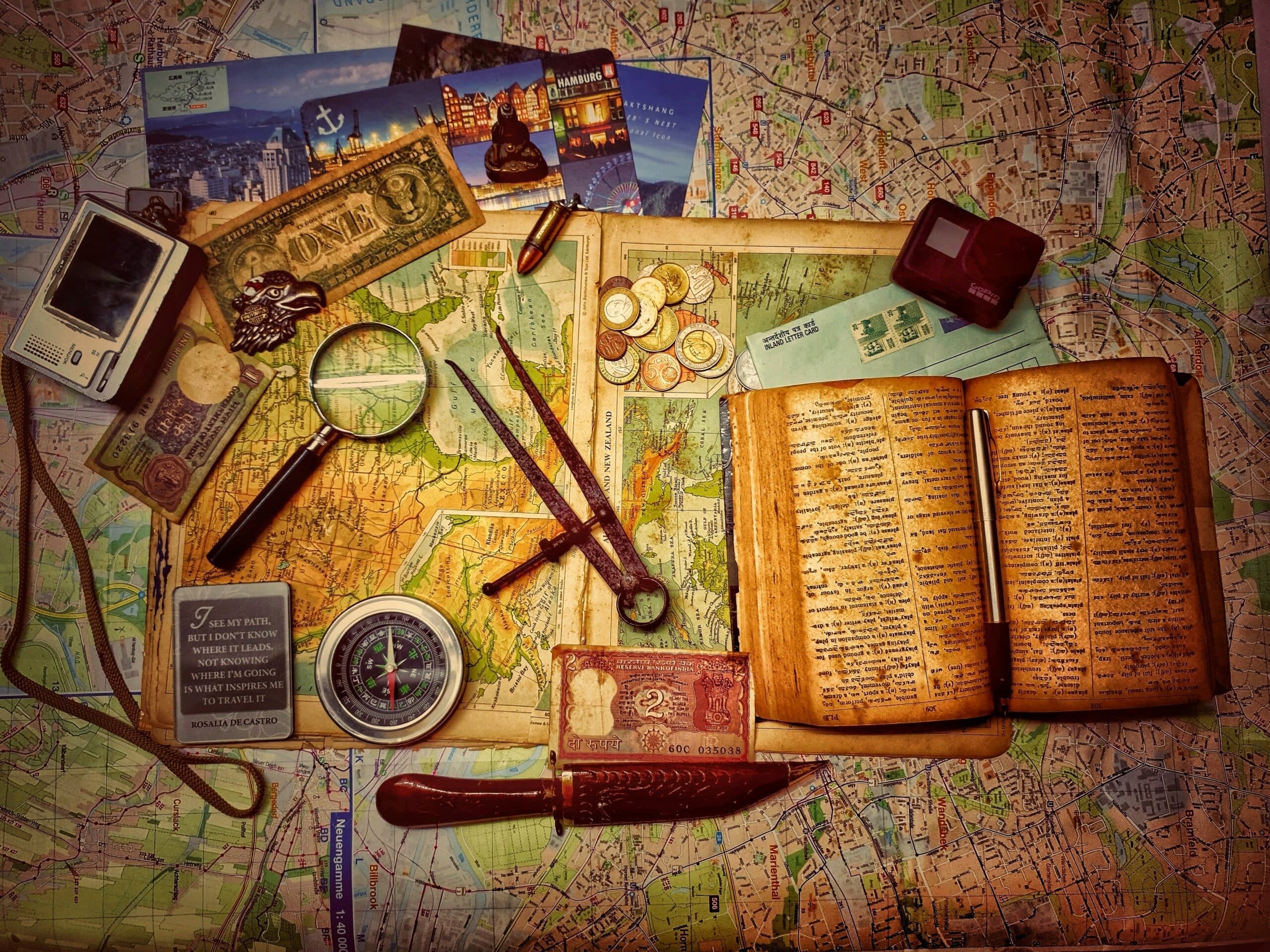 Old maps, a compass, a magnifying glass and coins laid out for a treasure hunt