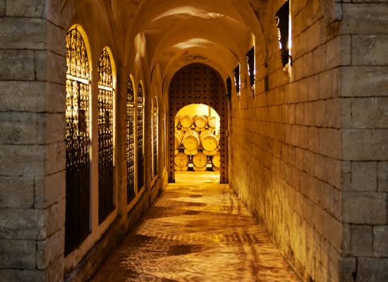 A stone cellar corridor leading to stacked barrels